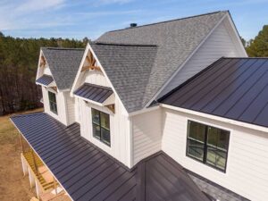Construction workers replacing shingles on a residential roof under a clear sky.